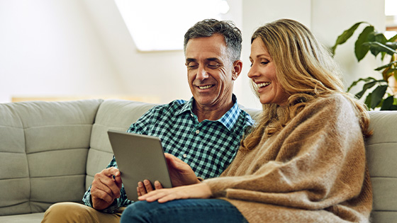 A couple on the couch looking at a tablet