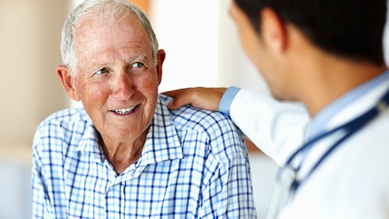 A clinician with his hand on his patients shoulder.